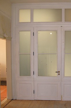 Die Innenseite der Tr in einer weien Fabfassung, das opake Glas trennt Treppenhaus und Flur.
