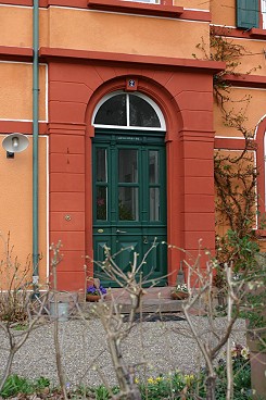 Die krftigen Farbkontraste, rot fr die Wnde, grn fr die Holzbauteile, lenken trotz des dunklen Farbtons den Blick auf die Haustr.